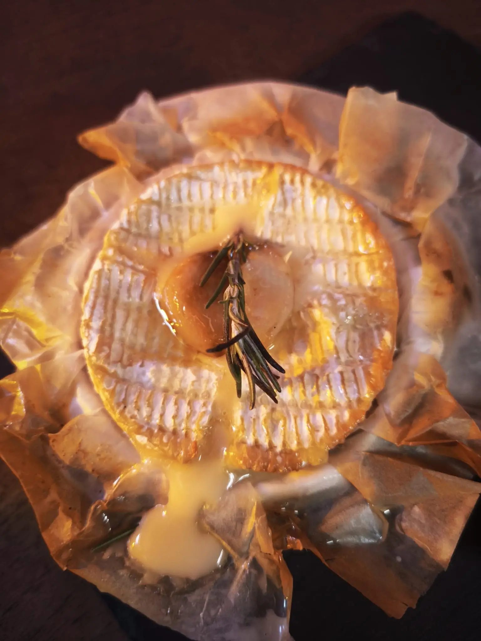 Camembert rôti au romarin dans son papier, servi avec des tranches de pain grillé