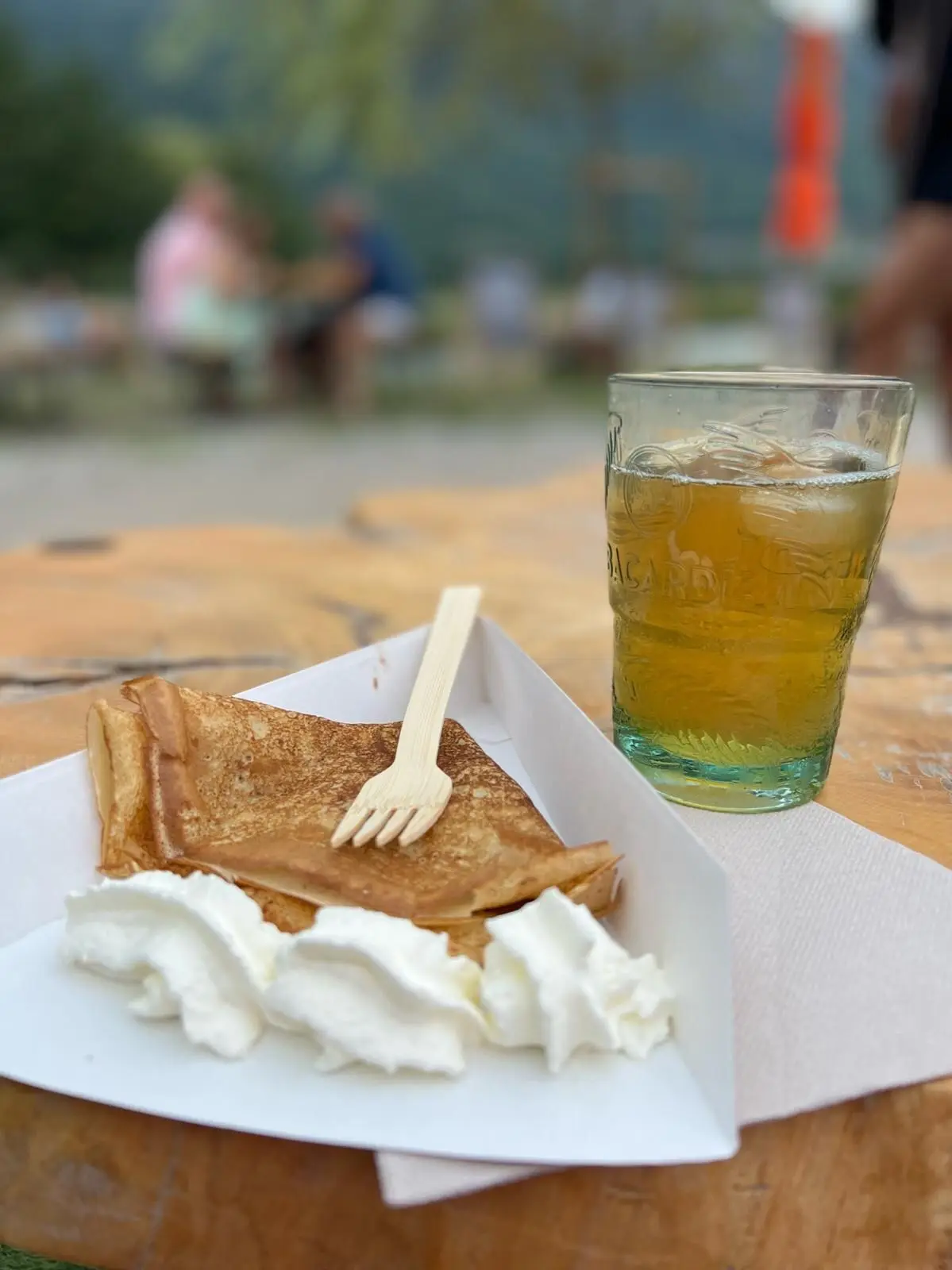 Crêpe pliée et chantilly servies dans une barquette, thé glacé à côté
