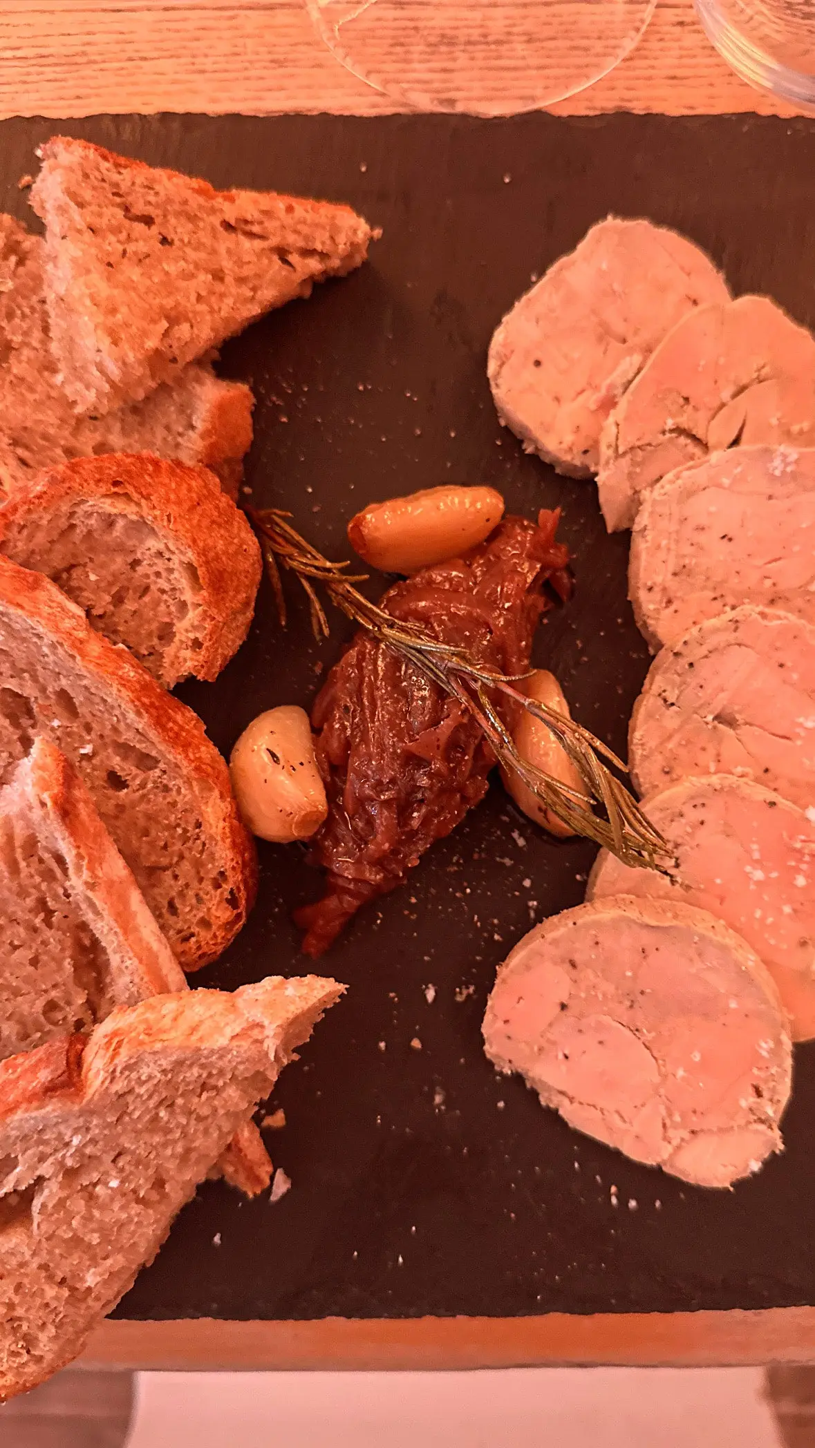 Tranches de foie gras sur ardoise, confit d'oignons, ail rôti et pain grillé