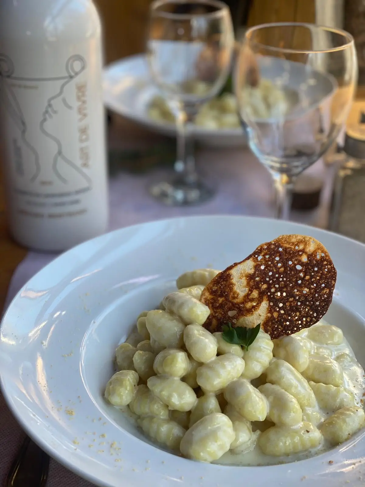 Gnocchis à la crème servis dans une assiette creuse, tuile de fromage gratiné posée dessus