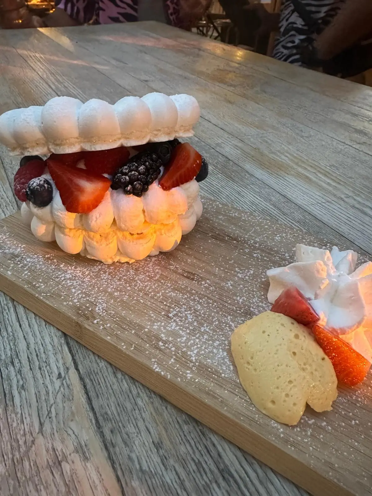 Grand entremets de meringue garni de fraises et de mûres, sur une planche en bois