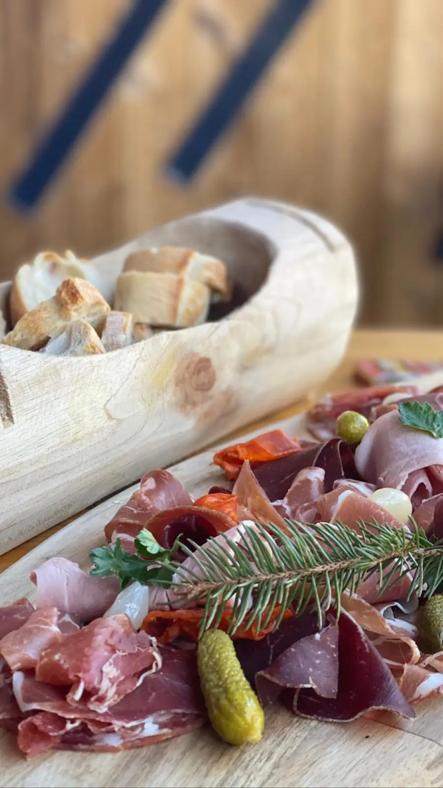 Planche de charcuteries, jambon cru, chorizo et cornichons, pain servi dans un sabot de bois