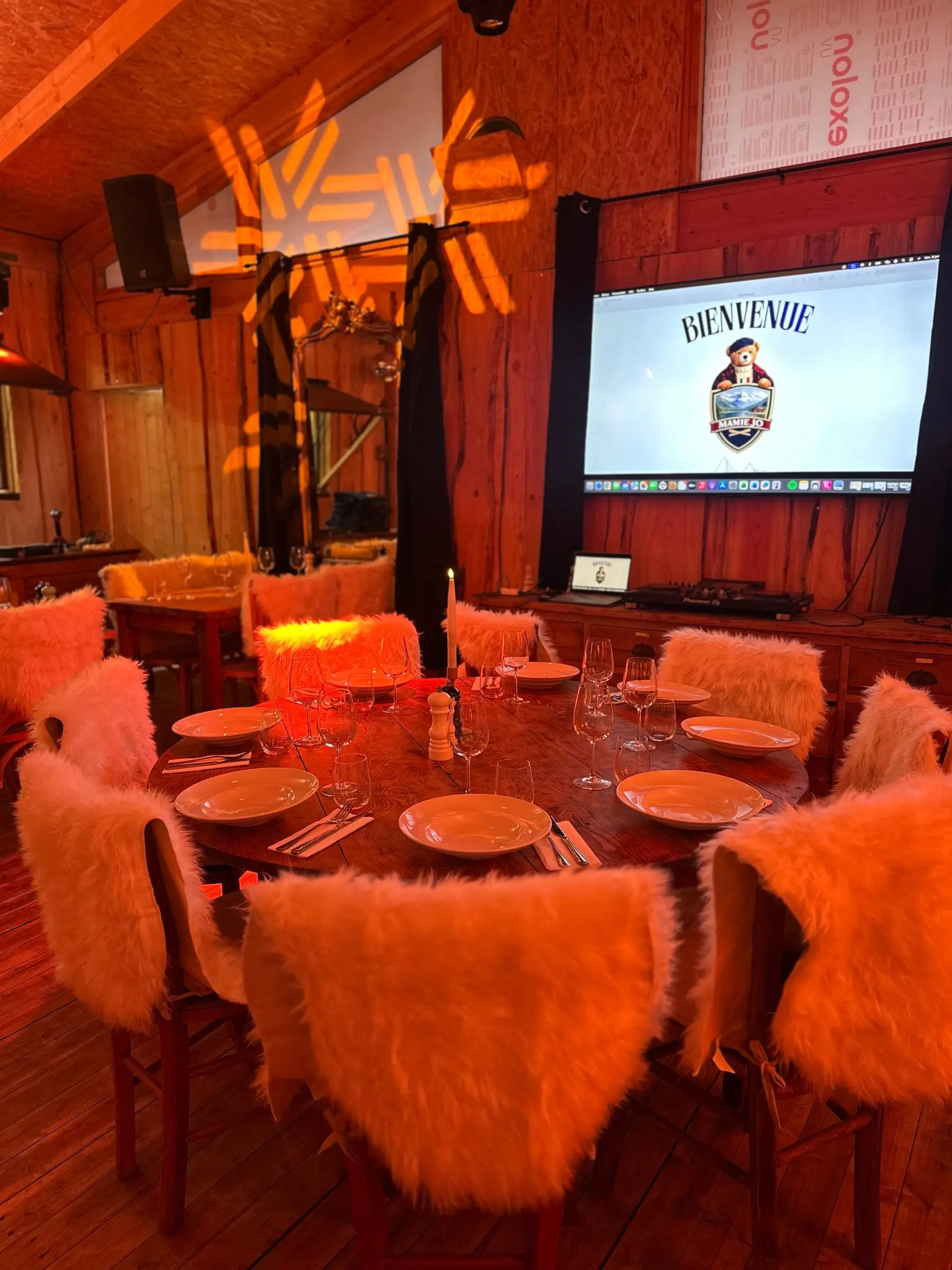 Table ronde dressée dans la salle du chalet, écran de projection et sono en fond